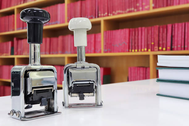 Self-inking, rubber date stamp on the table. Background of shelves with books in library.